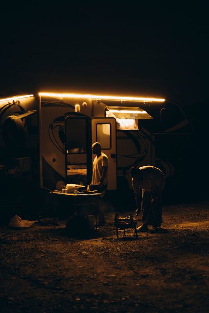Desert night camping scene near an RV in Showkah, UAE, highlighting outdoor adventure.