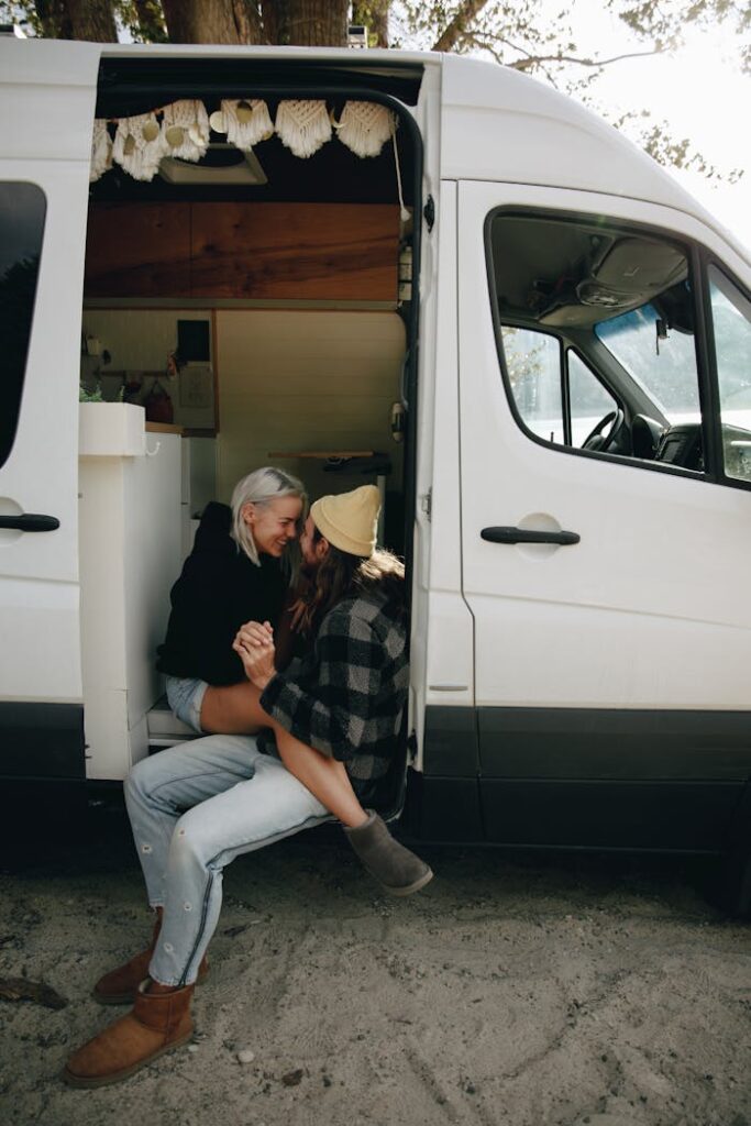 A loving couple shares an intimate moment sitting by their campervan during a road trip.