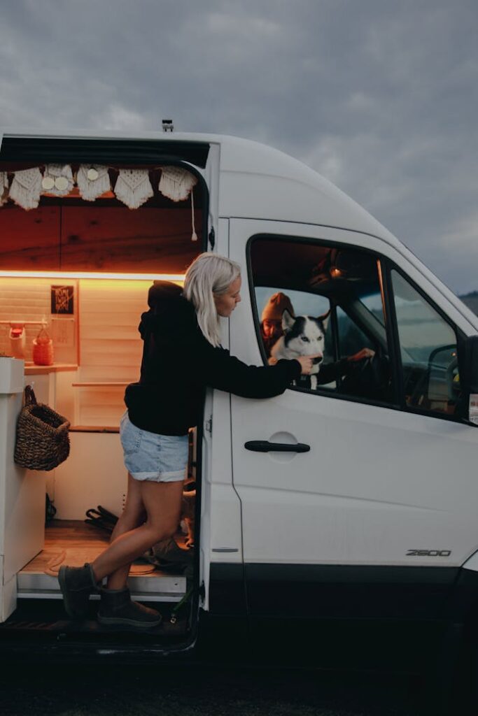 A woman in a campervan enjoys a moment with her dog, illustrating the nomadic van life.
